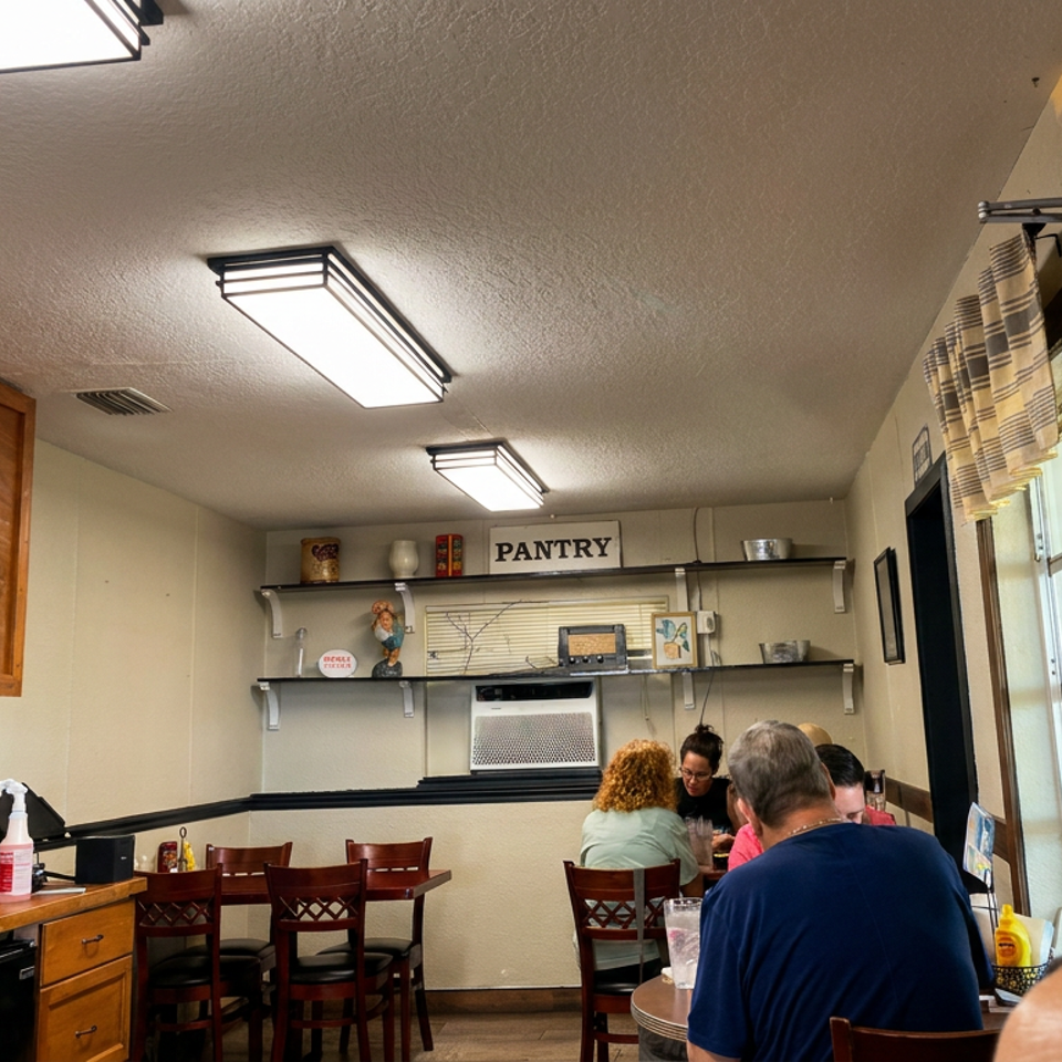 Cozy restaurant dining room with wooden cabinetry, counter seating, several diners, and a prominent PANTRY sign.